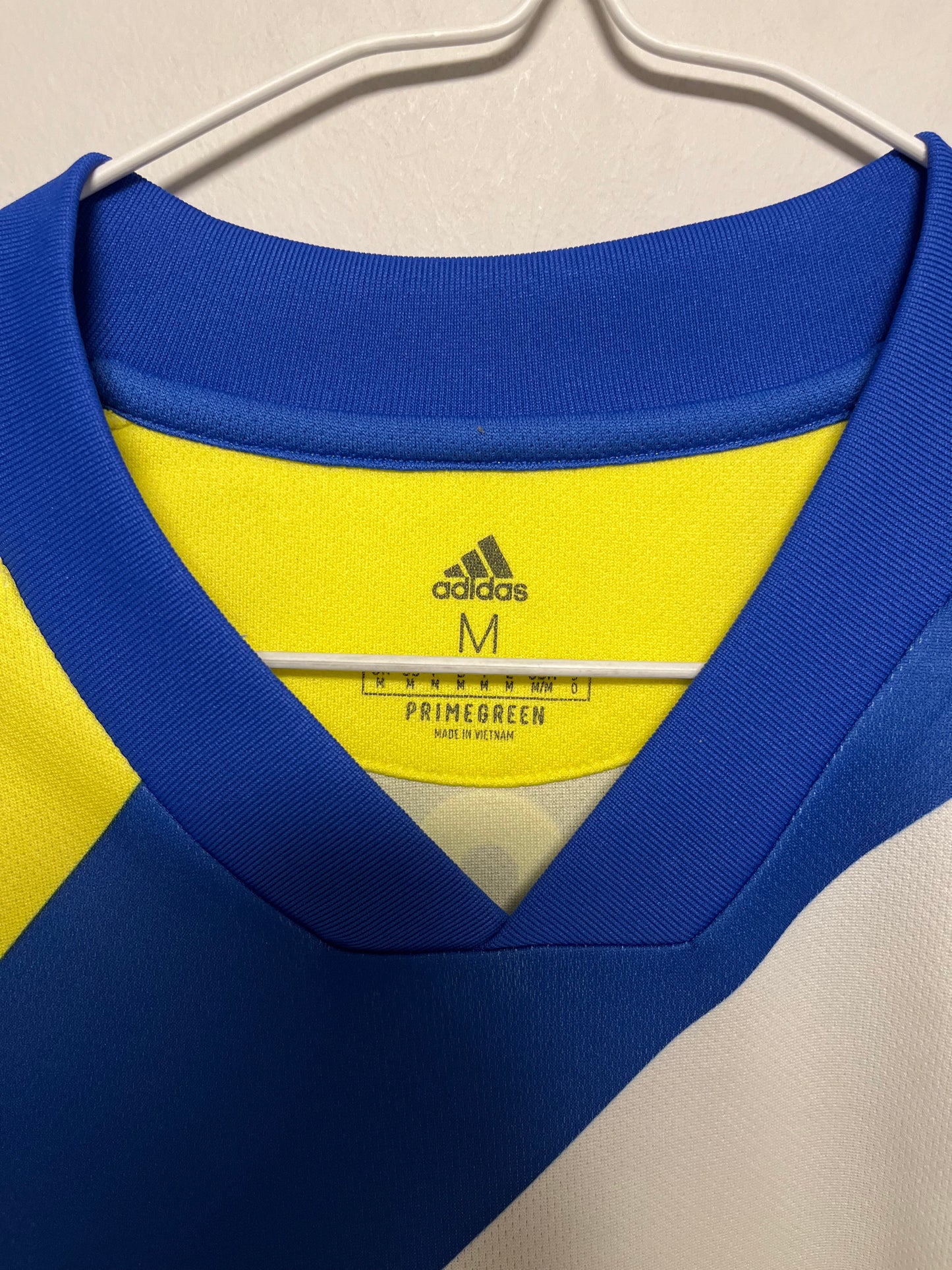 Close-up of a blue and yellow Adidas ranaldo 7  with a beige background