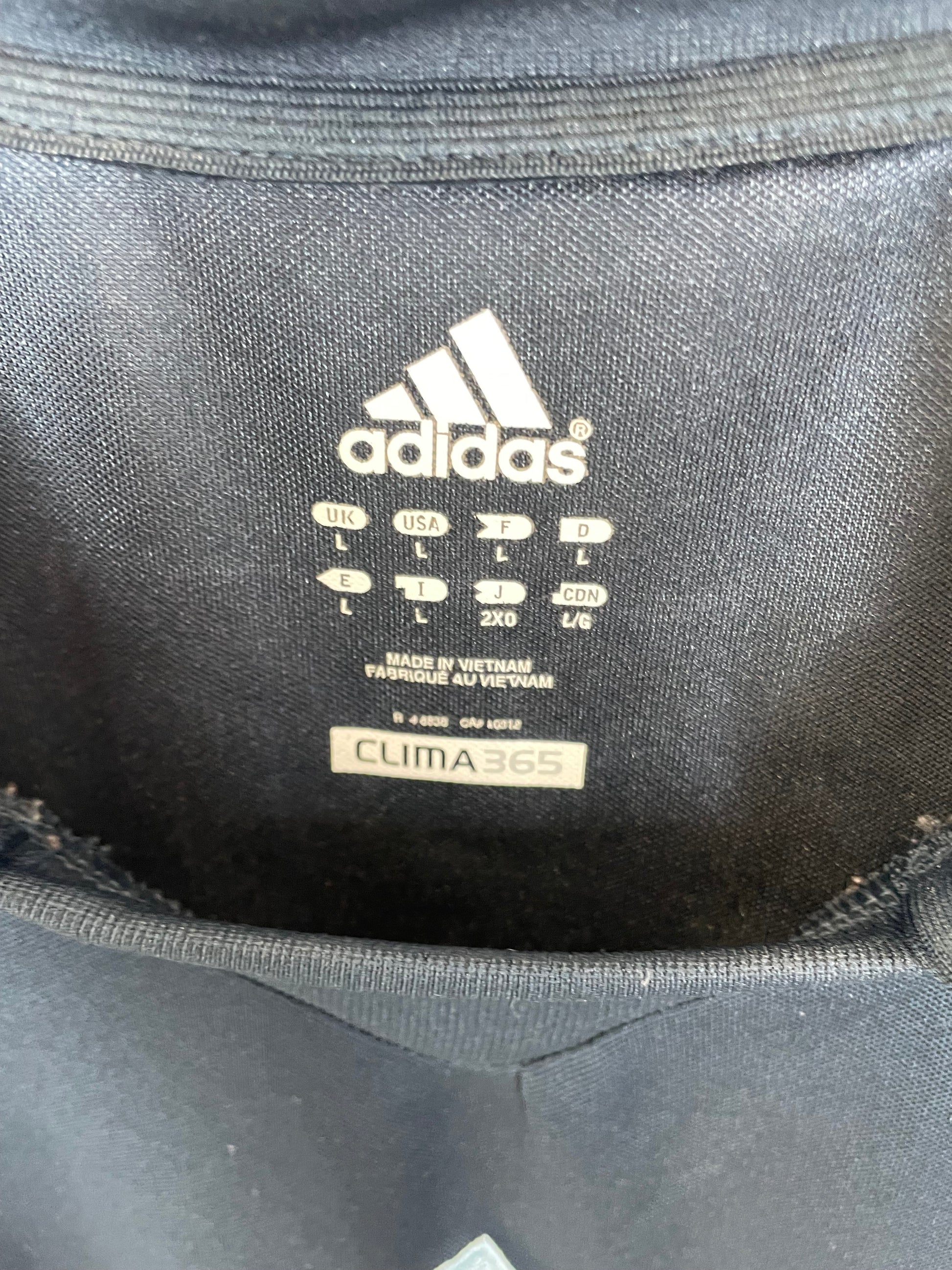Close-up of the interior lining of a black Adidas bag, showing the white Adidas logo, size information, and a beige CLIMAWA 350 label.