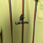 Close-up of a cream-colored shirt with red and blue stripes and 'Lacoste football shirt' branding.