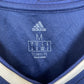 Close-up of a blue Adidas football shirt with branding and text.
