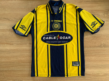 Rosario Central Home Shirt from 1998-1999: A classic representation of Rosario Central's home jersey during the 1998-1999 season. Featuring the club's emblem, it symbolizes the team's tradition and spirit on the field during that specific period.
