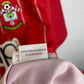 Close-up of the Southampton club crest on the 12/13 red and white striped home shirt, detail shot from our store